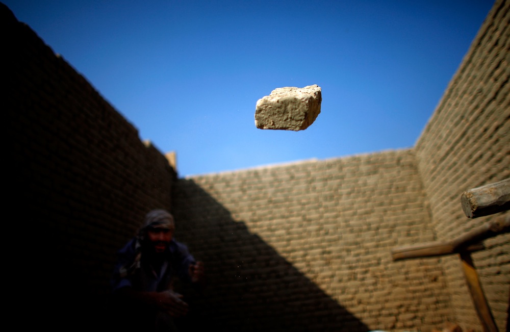 A worker throws an extra brick away from a newly constructed wall.