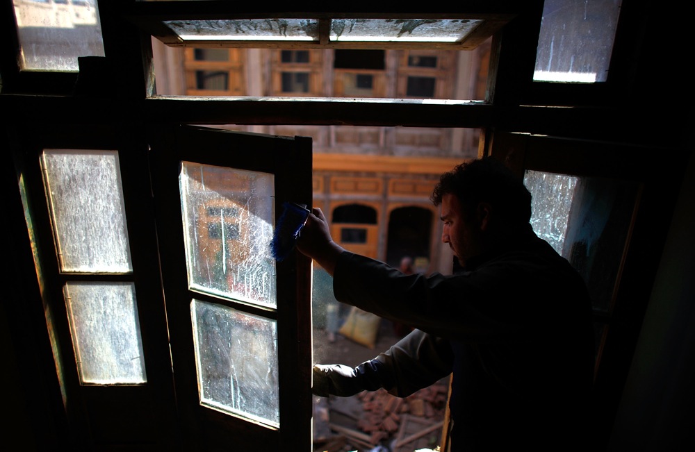 An Afghan window framer puts the finishing touches on a newly installed pane of glass. Emergency repairs to the quarter's private homes have made them structurally sound and weatherproof.
