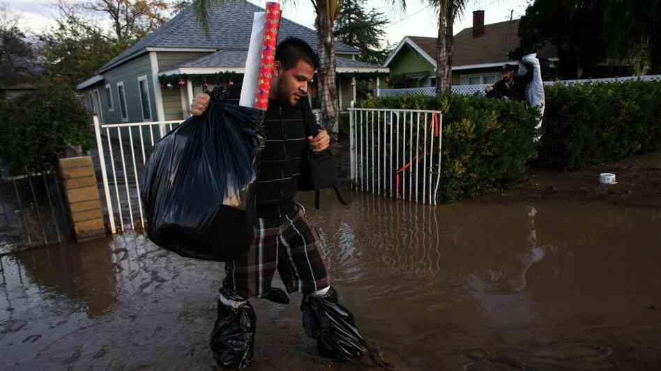 Allen Amparan carries Christmas presents from his home after flooding December 23, 2010 in Highland, California. Allen Amparan carries Christmas presents from his home after flooding December 23, 2010 in Highland, California.