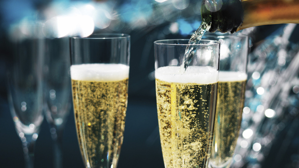Champagne being poured into champagne flutes, in a very sparkly, festive party.