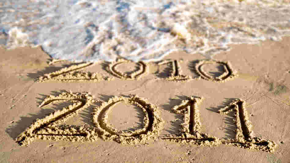 An ocean wave washes away the year 2010 written in beach sand.