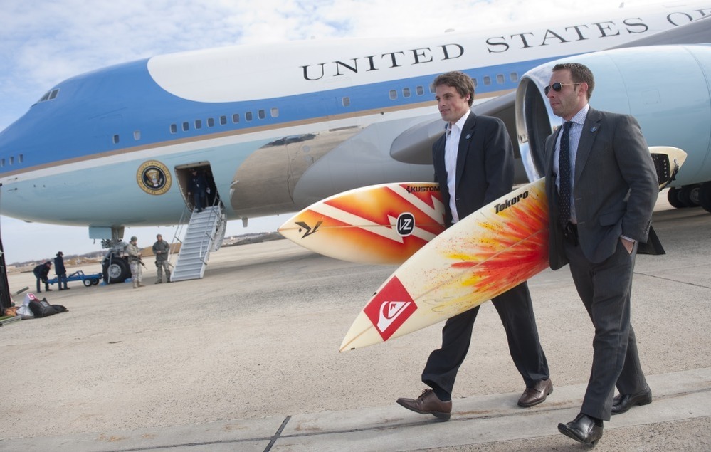 White House staffers Ben Finkenbinder and Nick Shapiro carry surfboards as they walk away from Air Force One after arriving with President Barack Obama at Andrews Air Force Base.
