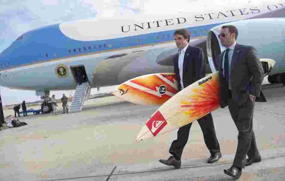 White House staffers Ben Finkenbinder and Nick Shapiro carry surfboards as they walk away from Air Force One after arriving with President Barack Obama at Andrews Air Force Base.