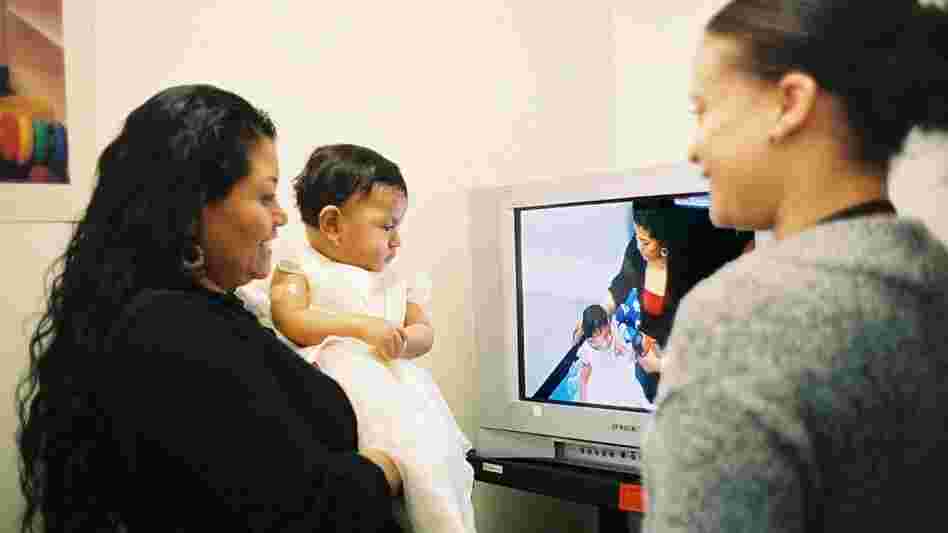 A mother watches a video taken of herself playing with her daughter for Bellevue Hospital's Video Interaction Project. Former hospital employee Brenda Woodford reviews the footage, offering positive feedback and areas for improvement.
