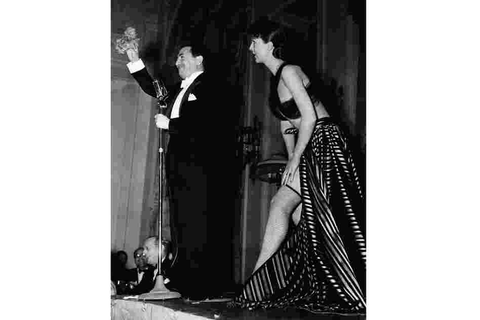 Gypsy Rose Lee delivers an $800 strip tease in New York at a benefit party for French war relief in 1940. The comedian Jack Pearl, left, acted as auctioneer, and movie actress Mary Pickford offered $400 for her to forget the strip tease, but the audience overruled the motion. 