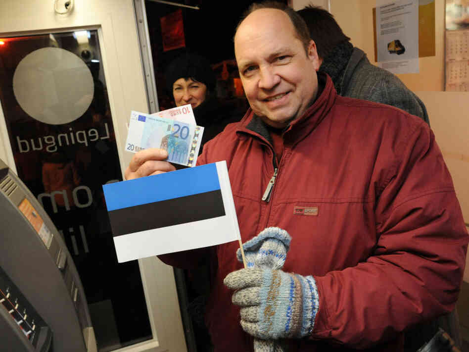 An Estonian man holds a national flag and new euro. An Estonian man holds a national flag and new euro.