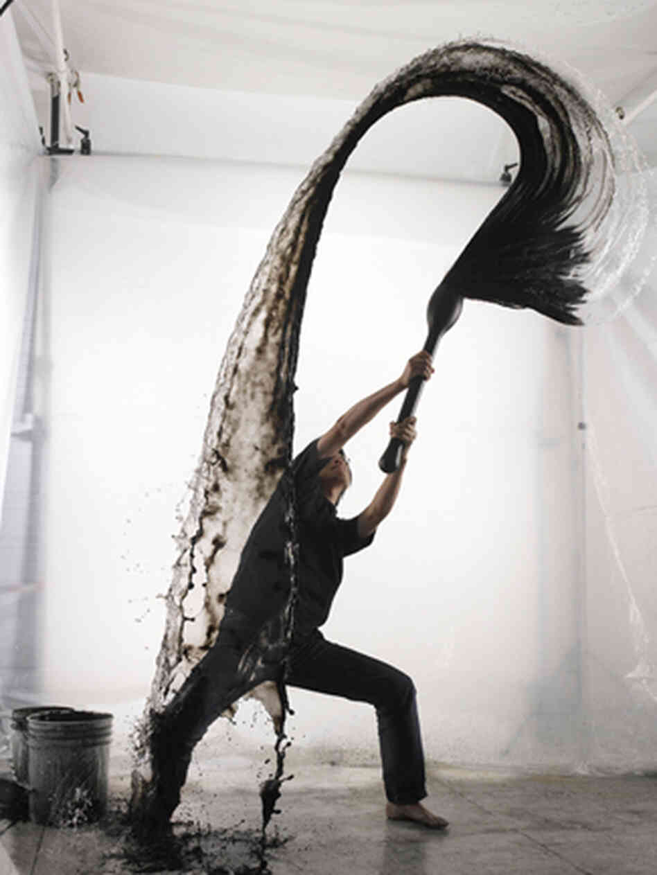 Artist Shinichi Maruyama throws a water and ink mixture in the studio while a camera captures his work. Artist Shinichi Maruyama throws a water and ink mixture in the studio while a camera captures his work.