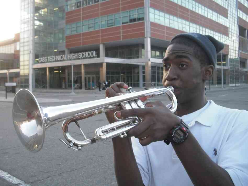 A student plays an instrument in front of the new Cass Tech High School building.