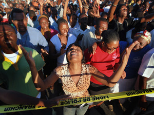 People attend a prayer service near the Presidential Palace in memory of those killed a year ago in the massive earthquake in Haiti. With much of the aid money unspent, the country struggles to repair the damage.