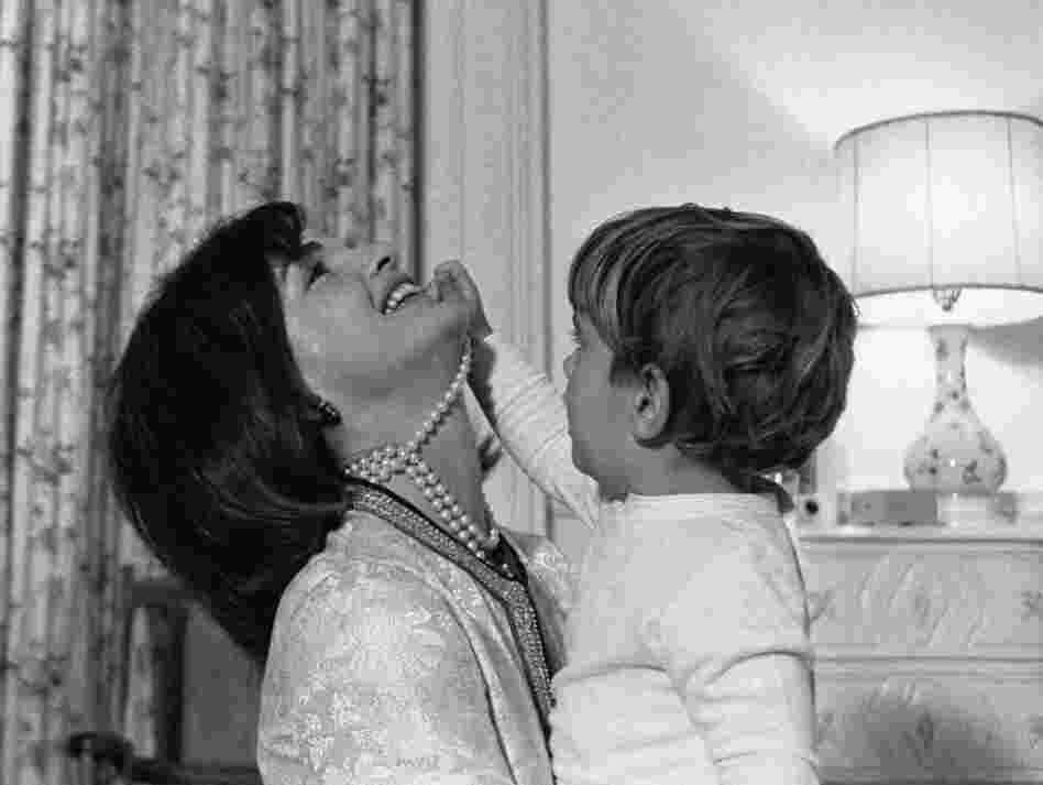 First lady Jacqueline Kennedy laughs as her son, John Jr., plays with her necklace in his White House bedroom in August 1962. 