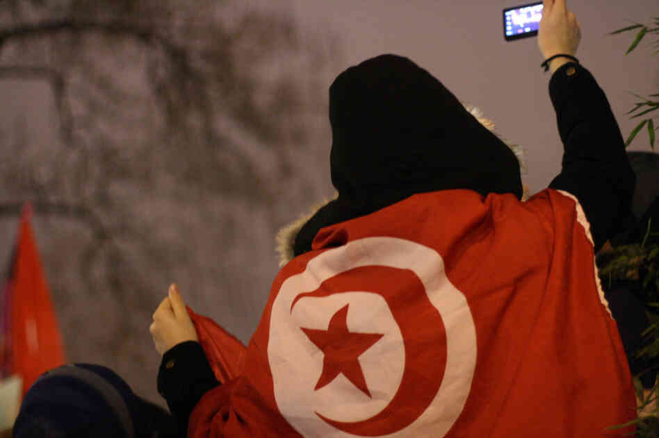 A woman uses her mobile phone to take a picture of a rally in Paris in support of protesters in Tunisia.
