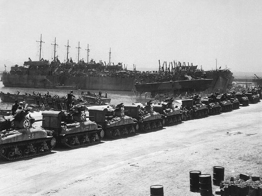 Tanks line up to board landing ships at the French Naval Base in Tunisia, July 1943.