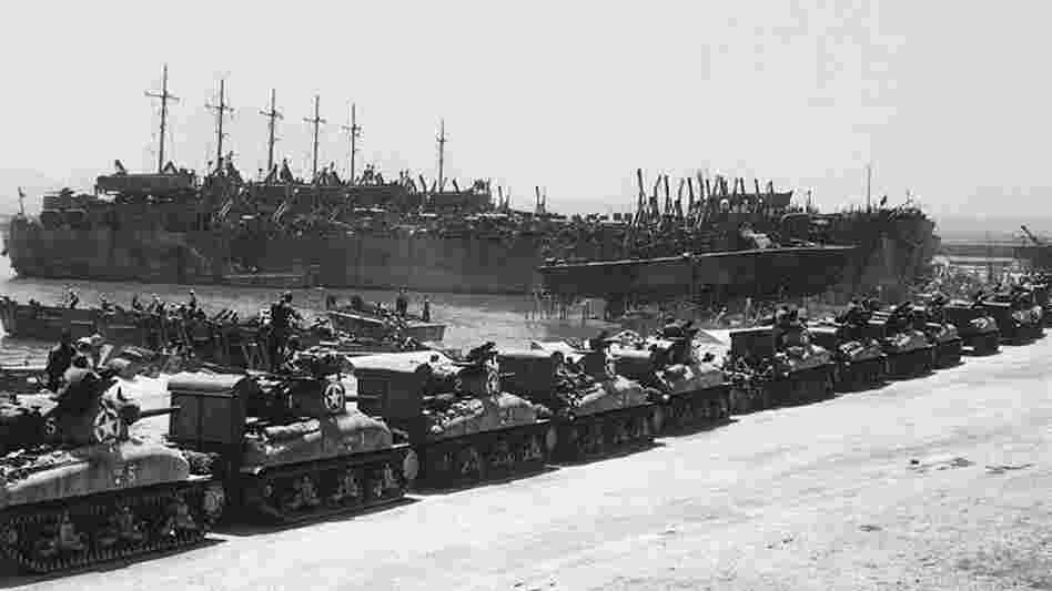 Tanks line up to board landing ships at the French Naval Base in Tunisia, July 1943.