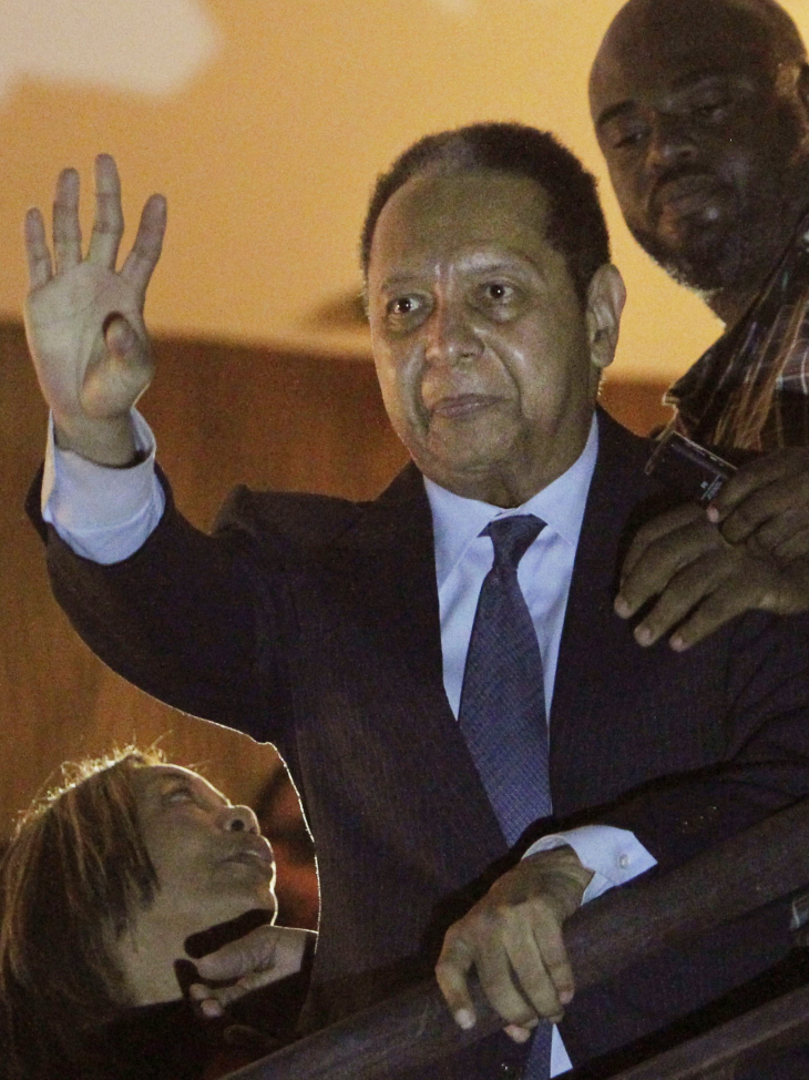 Haiti's former dictator Jean-Claude "Baby Doc" Duvalier, center, waves to supporters from a hotel balcony after his arrival in Port-au-Prince, Haiti on Sunday. Duvalier returned to the country after nearly 25 years in exile.