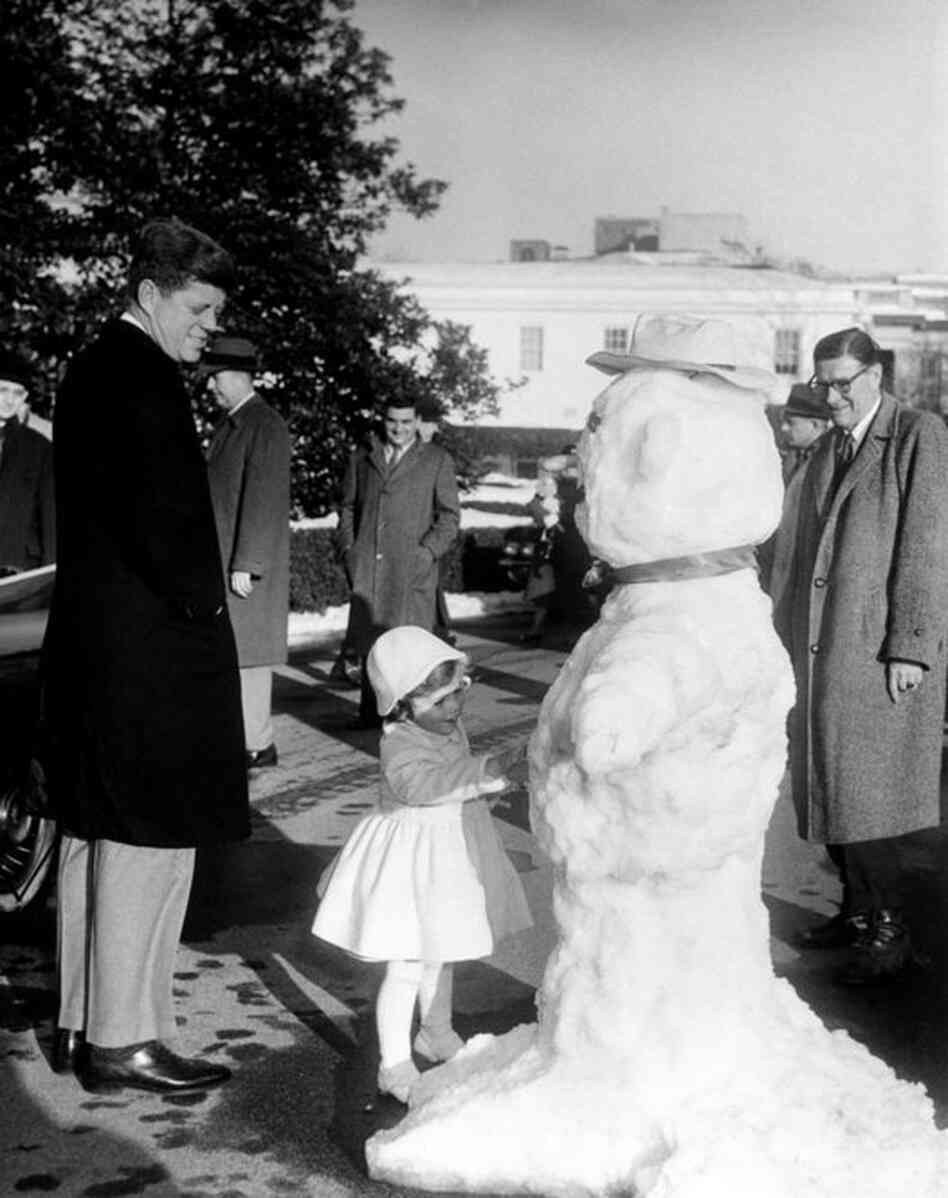 President  Kennedy watches his daughter Caroline inspect a snowman made for her on the White House driveway on Feb. 4, 1961. 