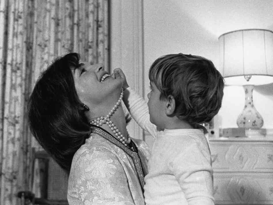 First lady Jacqueline Kennedy laughs as her son, John Jr., plays with her necklace in his White House bedroom in August 1962. 
