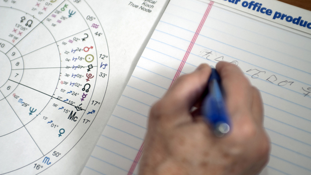An astrologist works on an astrological chart.