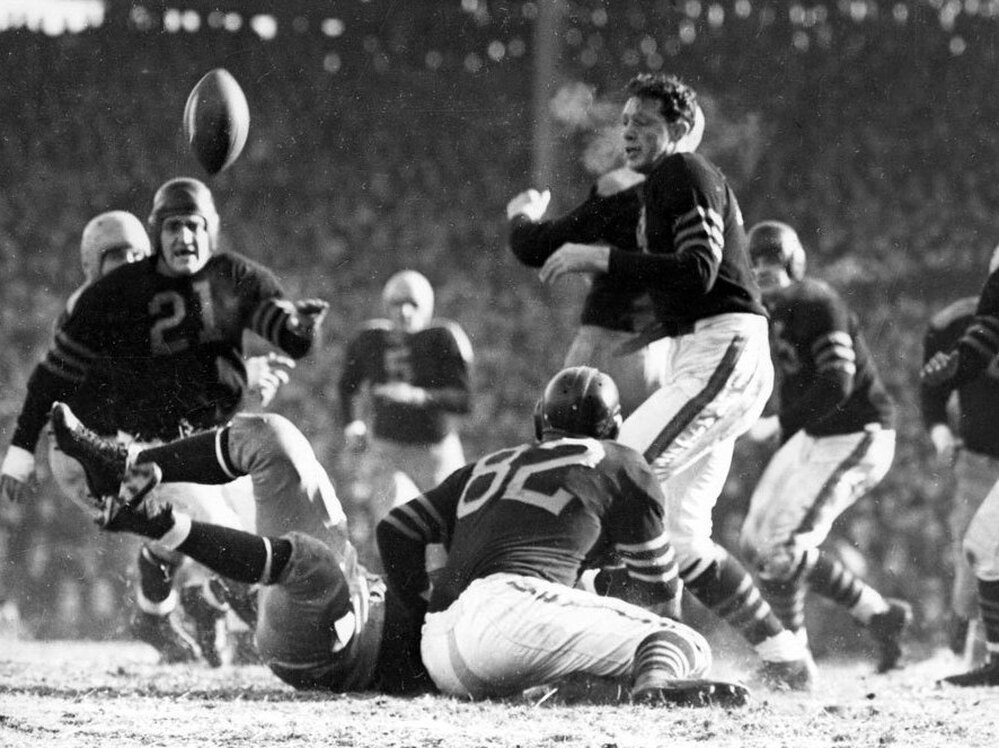 In the 1941 Western Division playoff game at Wrigley Field, Chicago Bears guard Danny Fortmann (21) gets a bead on the ball jarred loose by Bears guard Ray Bray (82).