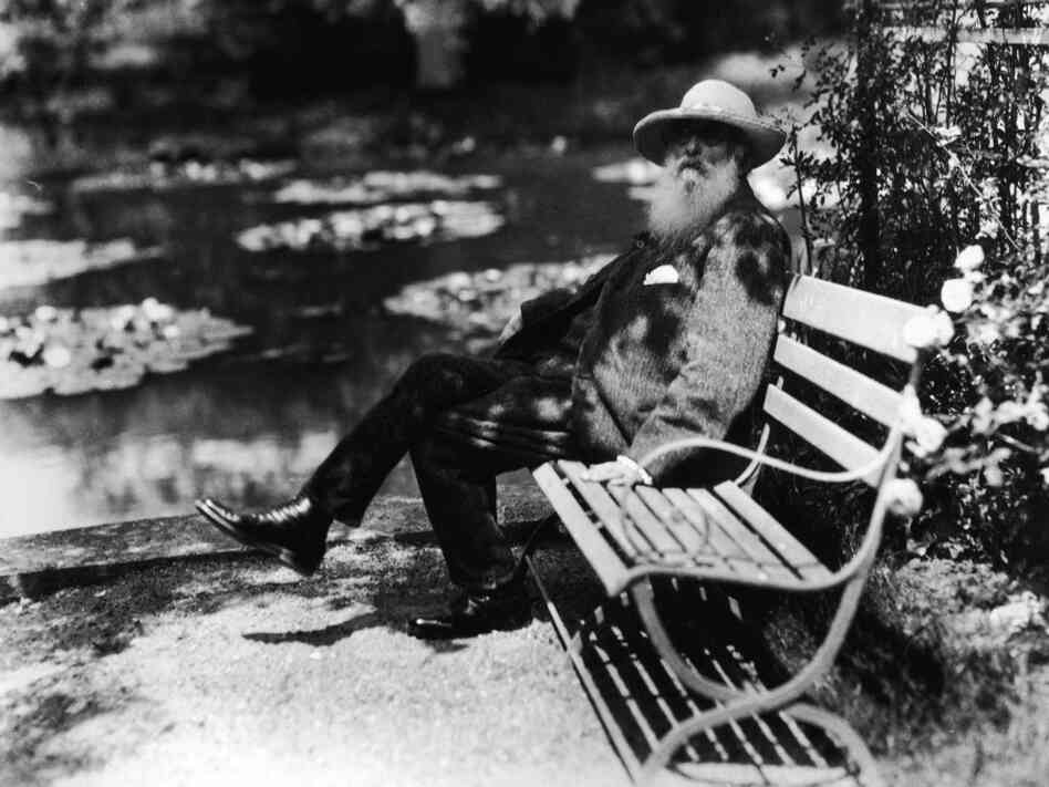 French impressionist painter Claude Monet sits beside the water lily pond in his home garden in Giverny, France, circa 1910.