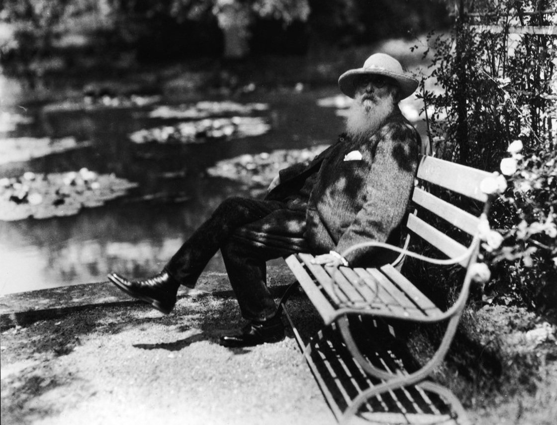 French impressionist painter Claude Monet sits beside the water lily pond in his home garden in Giverny, France, circa 1910.