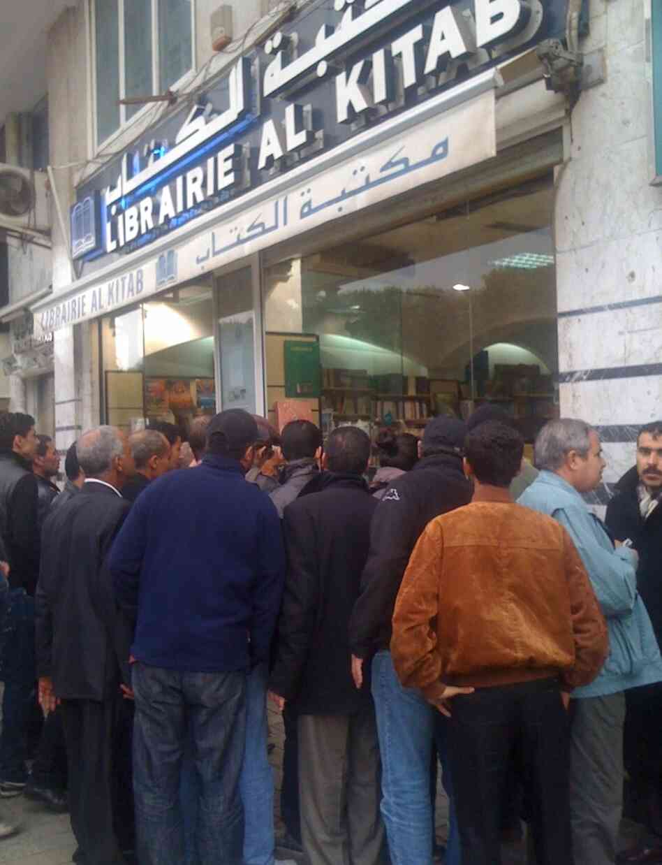 A crowd looks through the window of a Tunis bookstore at books that were previously banned.
