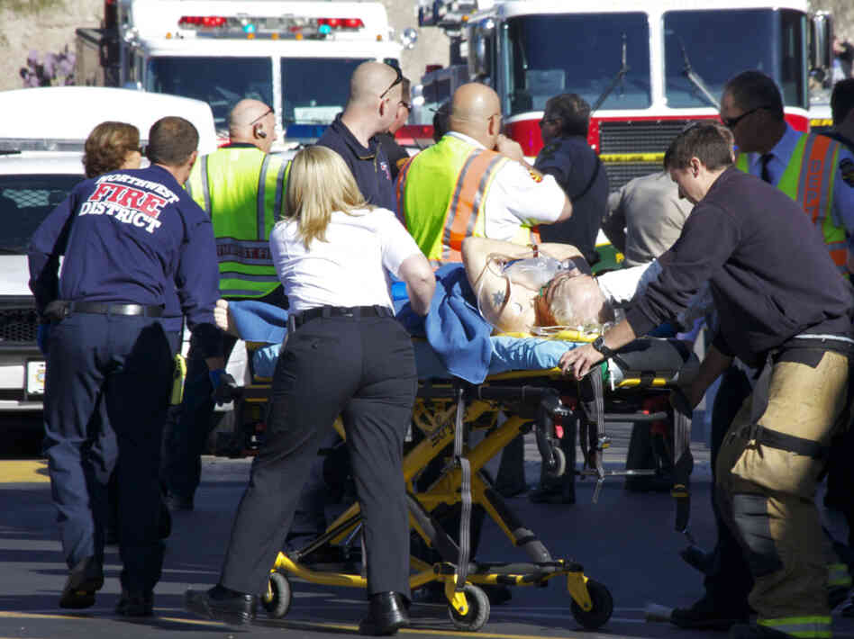 Emergency personnel attend to a shooting victim  outside a Safeway in Tucson, Ariz. Rep. Gabrielle Giffords (D-AZ), and others were shot as the congresswoman was meeting with constituents. First responders to the scene used special first aid kits to help treat victims until medical personnel arrived.
