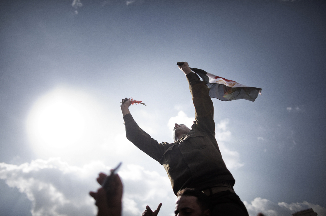 An Egyptian army Captain identified as Ihab Fathi holds the national flag while being carried by demonstrators during a protest in Tahrir Square in Cairo on the seventh day of mass protests calling for the removal of President Hosni Mubarak.