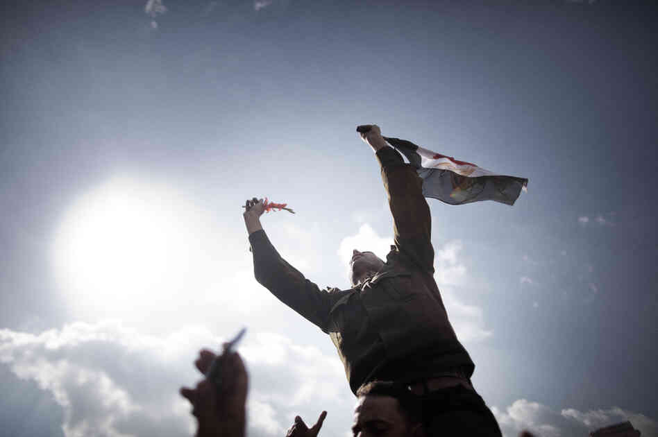 An Egyptian army Captain identified as Ihab Fathi holds the national flag while being carried by demonstrators during a protest in Tahrir Square in Cairo on the seventh day of mass protests calling for the removal of President Hosni Mubarak.