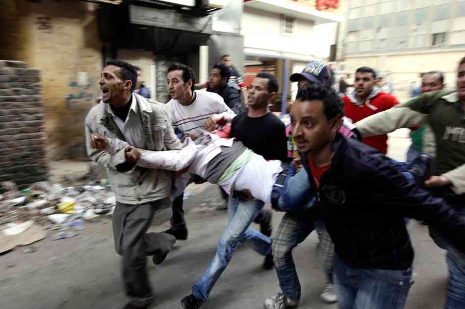 Egyptians carry an injured  protester during clashes with anti-riot police in Cairo on Saturday. 