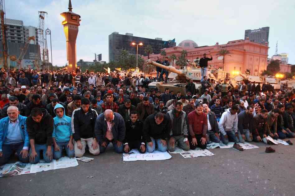 People pray in front of army tanks in Tahrir Square on Sunday, the sixth day of mass protests across the country calling for the resignation of long-term president, Hosni Mubarak. 
