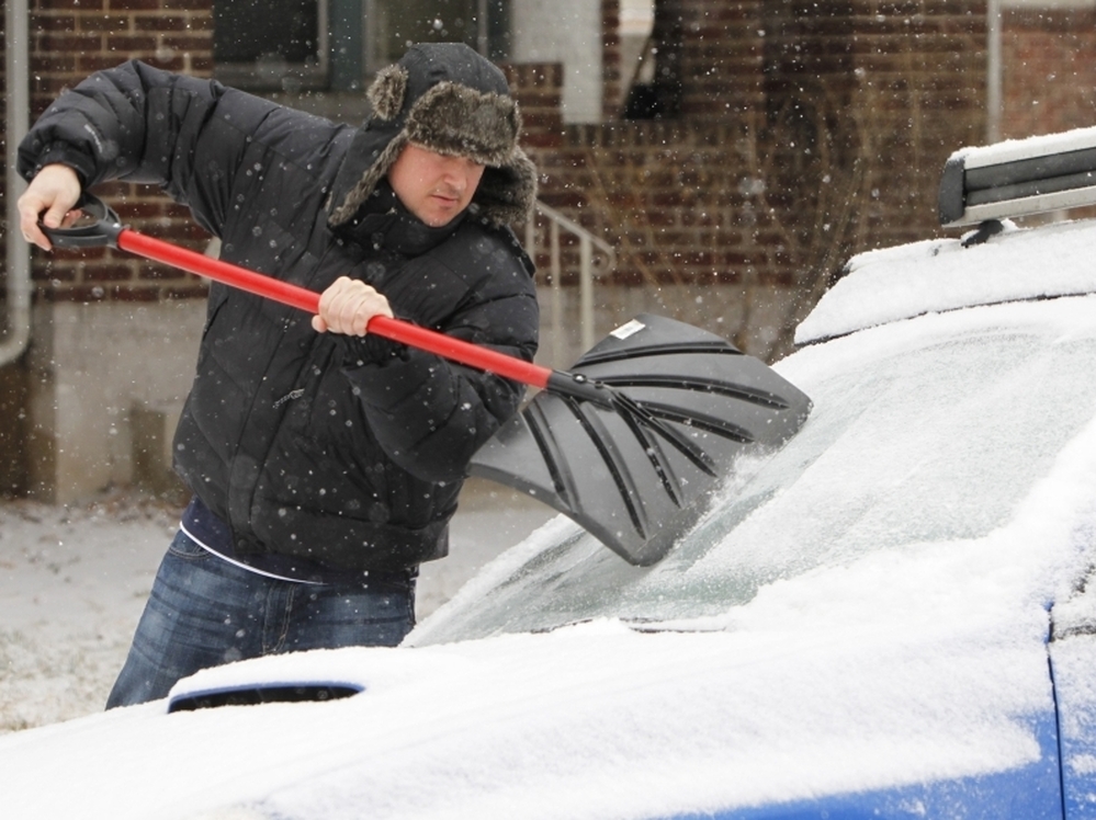 Tom Gillian uses a snow shovel to chip ice from his windshield in Denver on Monday. A monster winter storm is revving up in the Rockies and is expected to drop up to 2 feet of snow in some parts of the Midwest and an inch of ice in others.