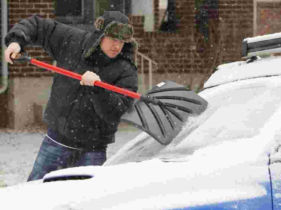 Tom Gillian uses a snow shovel to chip ice from his windshield in Denver on Monday. A monster winter storm is revving up in the Rockies and is expected to drop up to 2 feet of snow in some parts of the Midwest and an inch of ice in others.