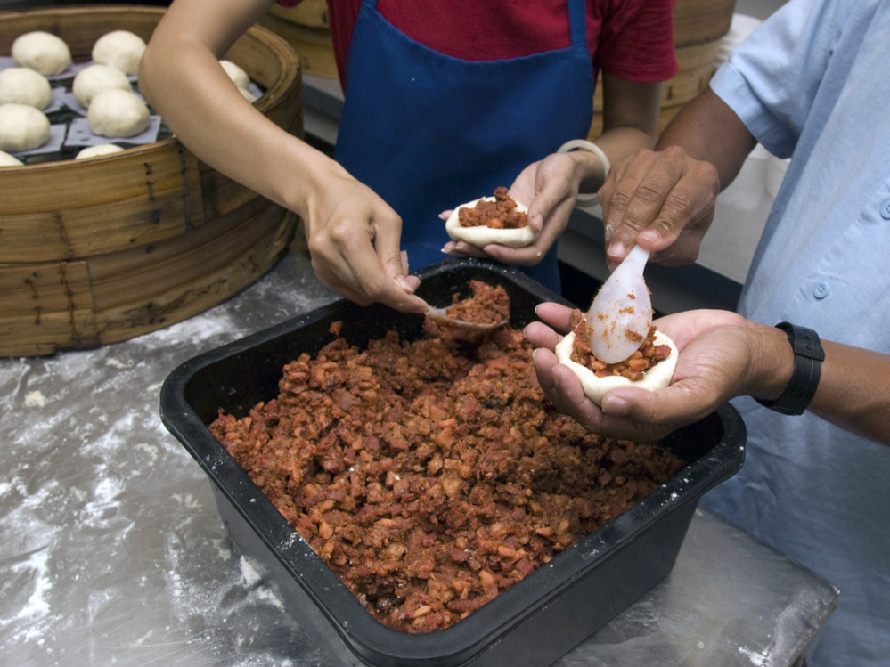 Workers at Shay Shay Tien make pow, placing the meat filling onto discs of dough that will go in a steamer basket