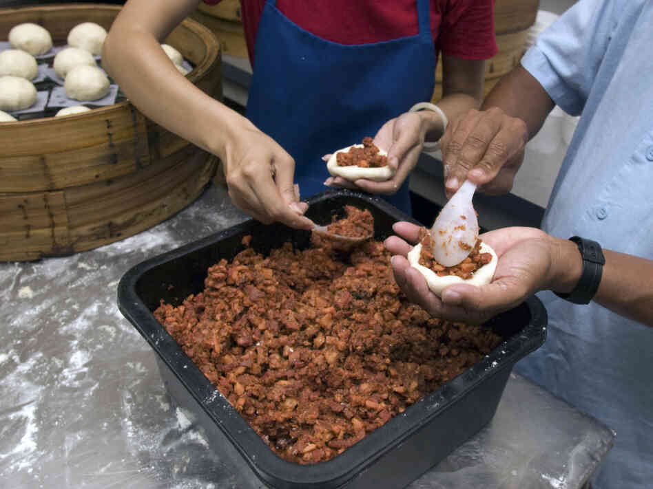 Workers at Shay Shay Tien make pow, placing the meat filling onto discs of dough that will go in a steamer basket