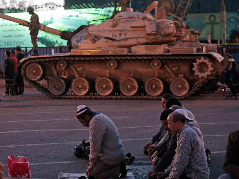 Anti-government  protesters offer their evening prayers in front of an Egyptian army tank securing the area during a protest Monday in Cairo's Tahrir Square.