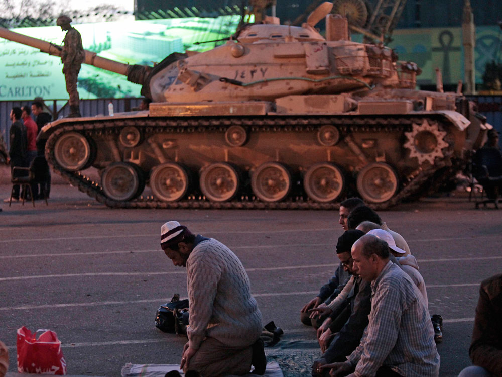 Anti-government  protesters offer their evening prayers in front of an Egyptian army tank securing the area during a protest Monday in Cairo's Tahrir Square.
