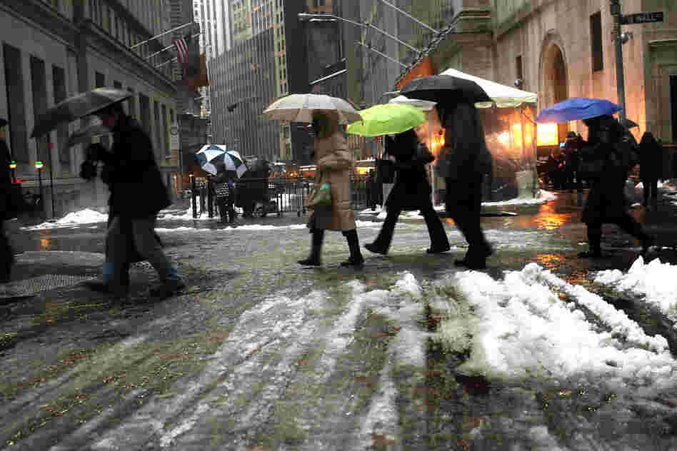 Pedestrians make their way through freezing rain during the morning commute along Wall Street on Wednesday in New York City. 