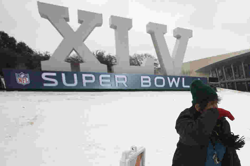 An Australian football fan is blown by a gust of wind after posing for photos in front of Cowboys Stadium in Arlington, Texas. In town for Sunday's Super Bowl, she says this is the first time she has experienced snow. 