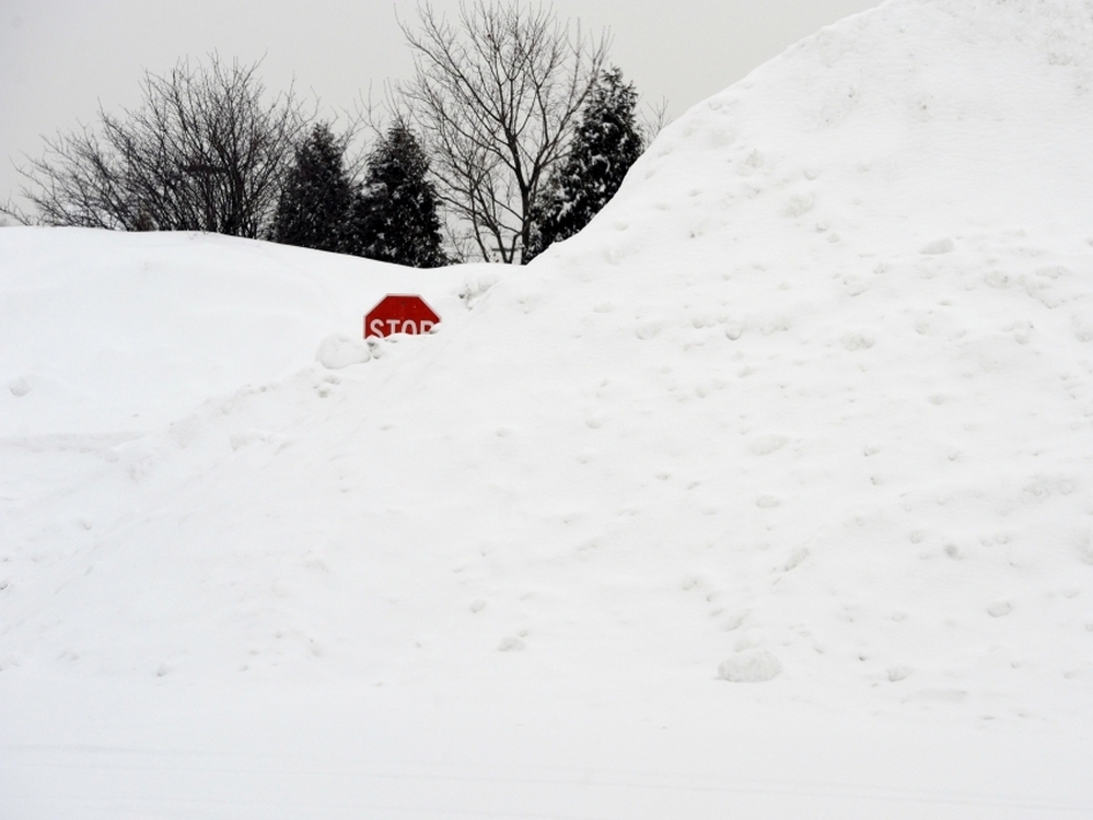 A stop sign pokes out of a large pile of snow at the end of a street in Enfield, Conn., on Tuesday.