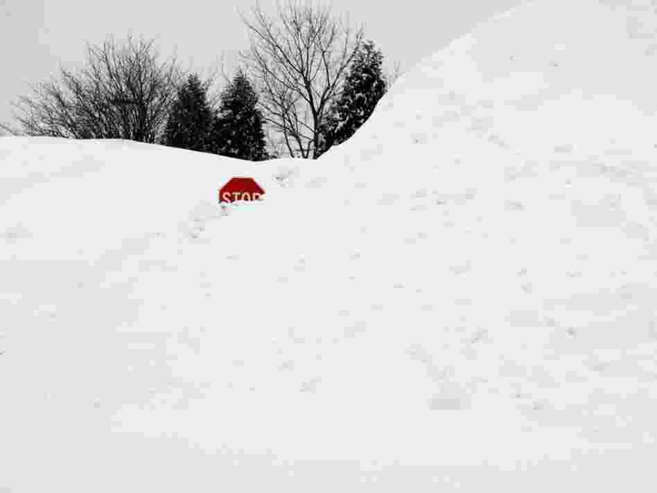 A stop sign pokes out of a large pile of snow at the end of a street in Enfield, Conn., on Tuesday.