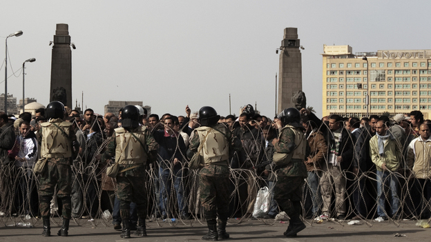 Egyptian soldiers stand behind barbed wire at the entrance of Cairo's Tahrir Square as anti-government demonstrators gather Friday.