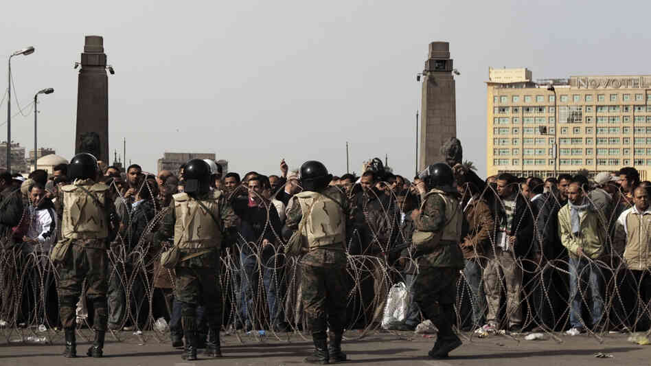 Egyptian soldiers stand behind barbed wire at the entrance of Cairo's Tahrir Square as anti-government demonstrators gather Friday.