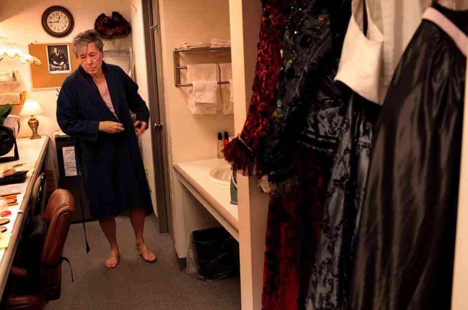 Bedford puts on an old tie-dyed T-shirt and robe, and goes to the makeup table to begin.