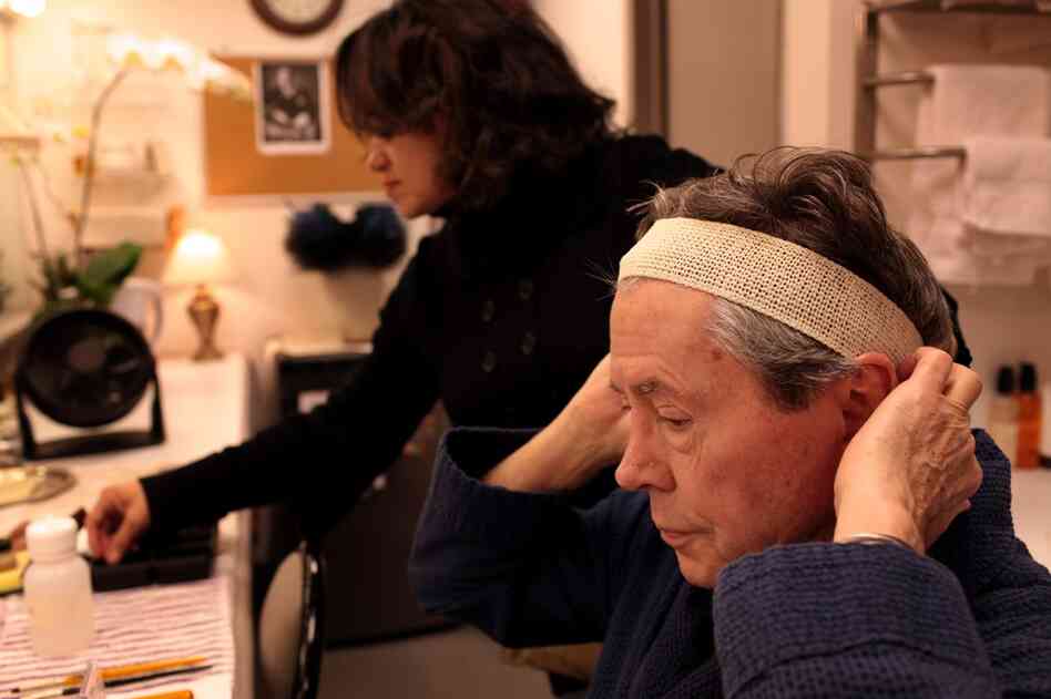 Before they get started with the makeup, hair and wig supervisor Nellie Laporte helps Bedford put on a wig cap. The wig itself will come later.