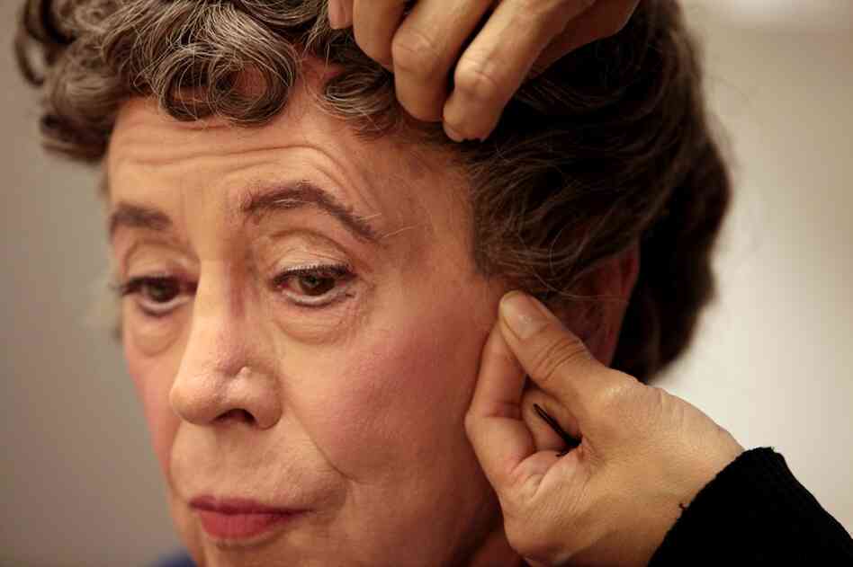 Nellie Laporte carefully slides Lady Bracknell's wig on over Bedford's wig cap.
