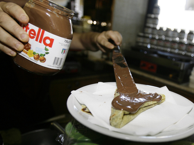 A bartender spreads Nutella on a crepe in a Rome creperie.