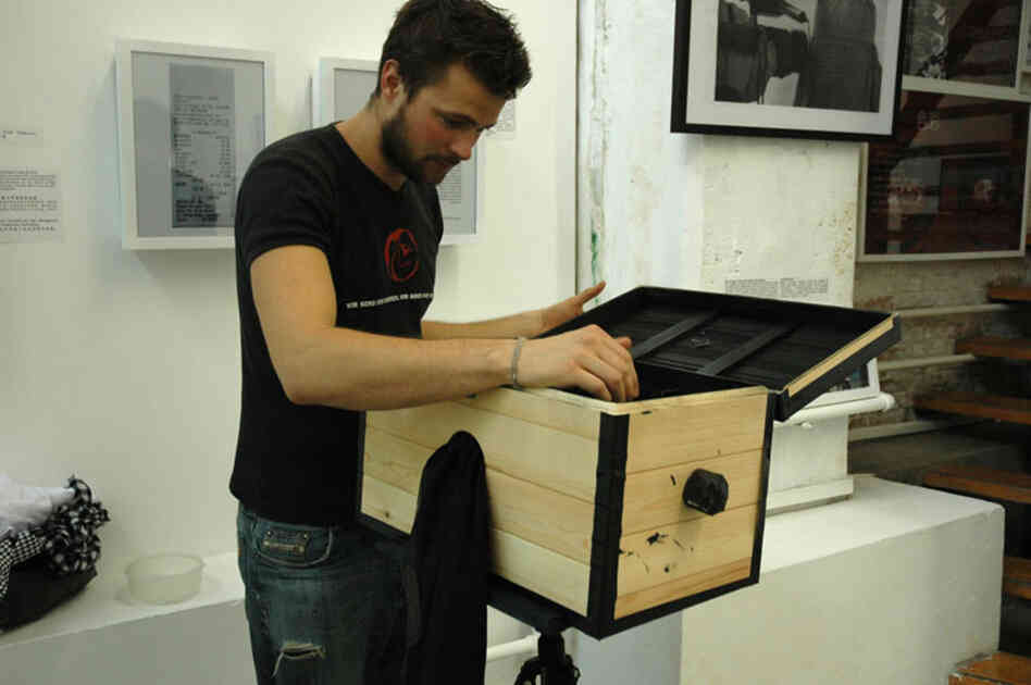Birk and the first incarnation of his box camera, at an exhibition for some of his other work in Beijing in 2009. The black cloth hanging from the side covers a hole through which he can reach his hand to mount and develop the photo paper while preventing light from entering.