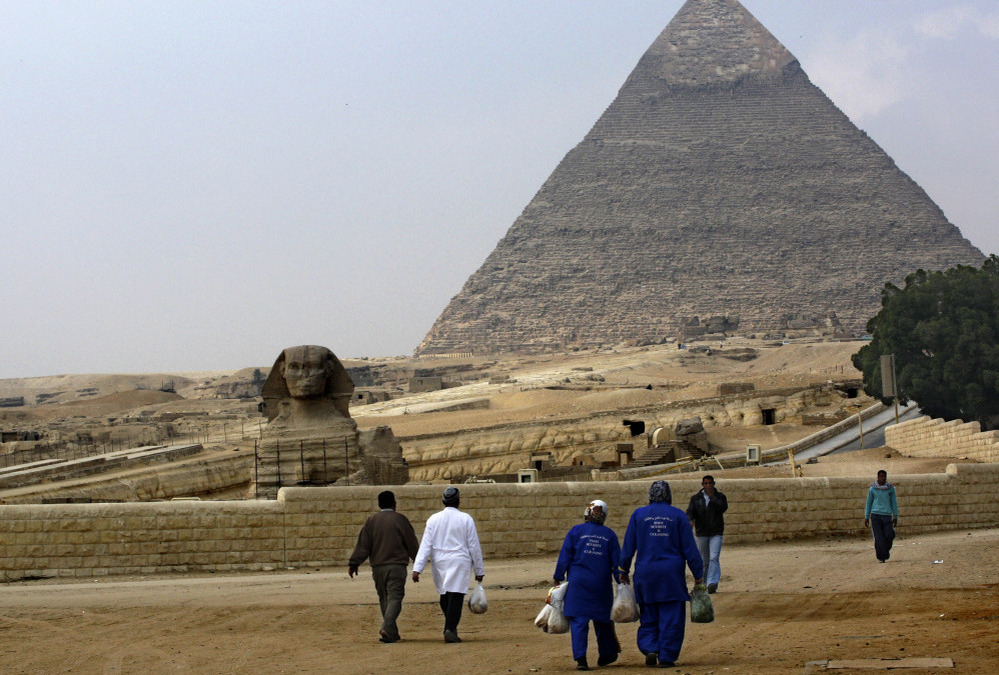 Street cleaners walk through the deserted pyramids site in Giza, one of Egypt's most famous tourist attractions, on Monday.