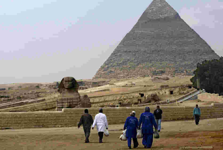 Street cleaners walk through the deserted pyramids site in Giza, one of Egypt's most famous tourist attractions, on Monday.