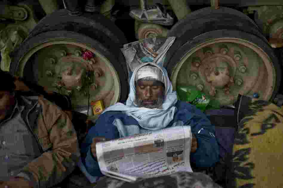 A protester reads a newspaper while resting against an army tank in Tahrir Square on Friday. 